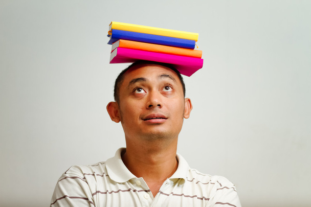 Етнічний молодий чоловік з книгами на голові
 - Фото, зображення