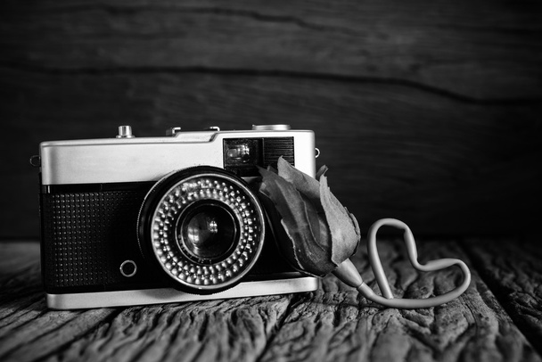 Εκλεκτής ποιότητας φωτογραφική μηχανή με τριαντάφυλλο σε μαύρο και άσπρο φίλτρο. - Φωτογραφία, εικόνα