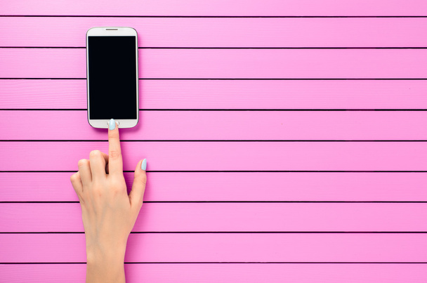 Female hand using white mobile phone over pink background - Fotografie, Obrázek