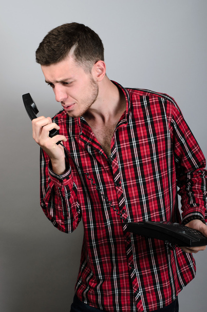 Angry businessman yelling into landline phone on grey - Foto, Bild