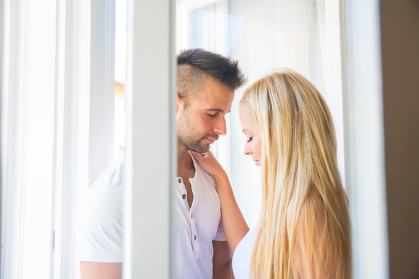 Beautiful young couple standing at the window		 - Fotografie, Obrázek