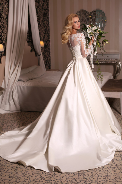 gorgeous woman with blond hair wears luxurious wedding dress with bouquet - Фото, зображення