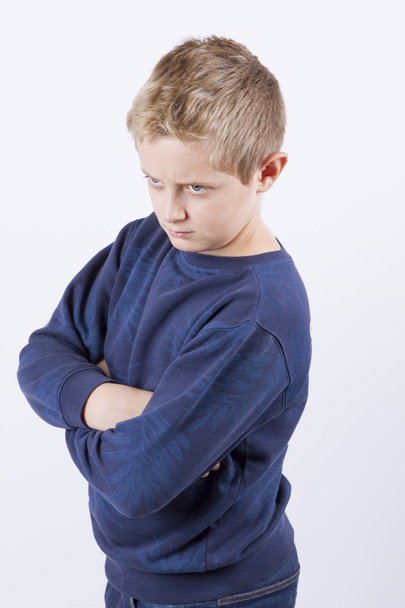 Nahaufnahme Porträt eines unzufriedenen, angepisst, wütenden, mürrischen Jungen mit blauen Augen - Foto, Bild