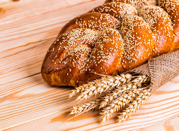 Two whole fresh challah bread with poppy and sesame on a wooden  - Fotoğraf, Görsel