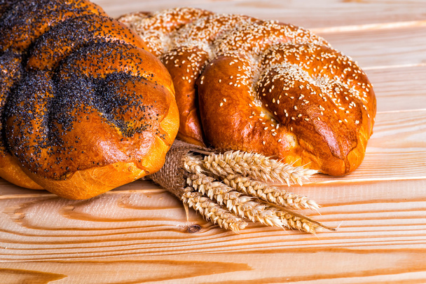 Two whole fresh challah bread with poppy and sesame on a wooden  - Foto, imagen