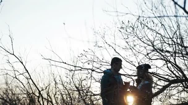 Fiatal szép pár csattogó szemüveg beszél és csók romantikus naplemente környezetben ébredő tavaszi természet - Felvétel, videó