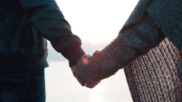手をつないでいるカップルのクローズアップ。海の波を見るために近づいてくる若い夢中のカップル - 映像、動画