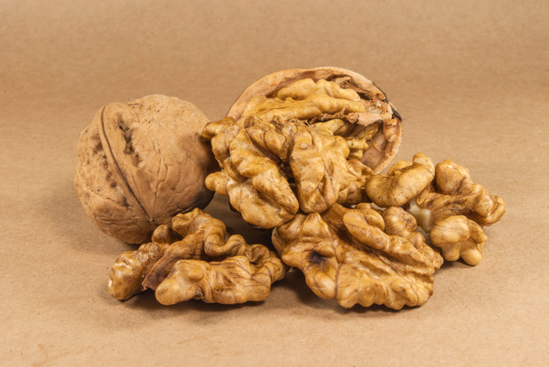 Ореховые ядра и целые грецкие орехи на крафт-бумаге, крупным планом
 - Фото, изображение