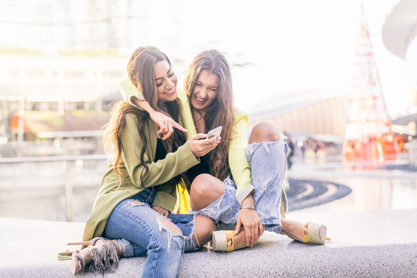 Girlfriends looking down at smartphone - Zdjęcie, obraz