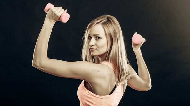 Chica fitness con mancuernas flexionando los músculos en el gimnasio
 - Foto, imagen