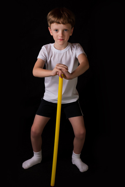Boy athlete performs exercises with gymnastic stick in the gym - 写真・画像