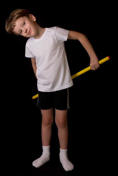 Menino atleta realiza exercícios com vara de ginástica no ginásio
 - Foto, Imagem