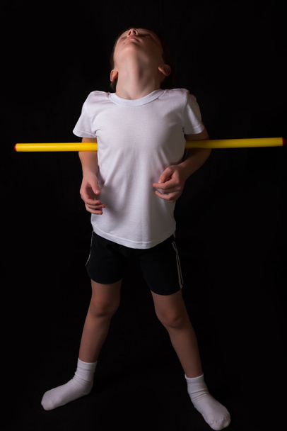 Jongen atleet voert oefeningen met gymnastiek stok in de sportschool - Foto, afbeelding