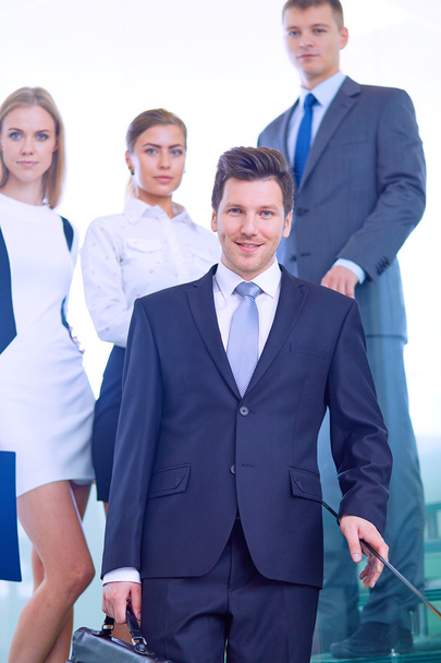 Portret van jonge zakenman in kantoor met collega's op de achtergrond - Foto, afbeelding