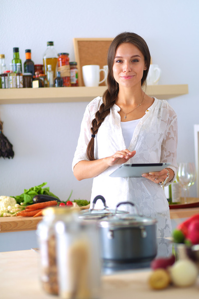 Young woman using a tablet computer to cook in her kitchen - Foto, Imagen