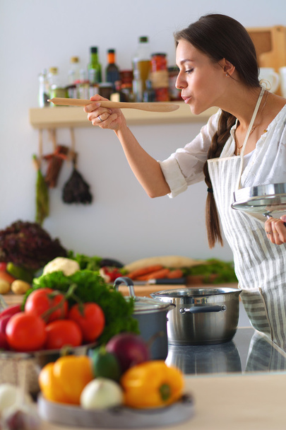 Koken vrouw in keuken met houten lepel - Foto, afbeelding