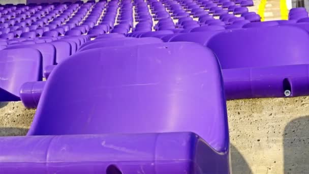 Filas de asientos de plástico violeta en el estadio tribune, dolly
 - Imágenes, Vídeo
