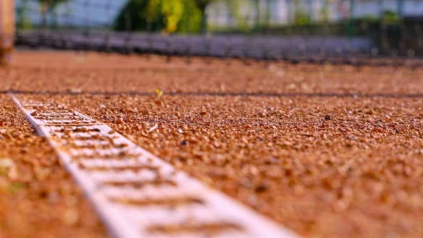 Una palla da tennis rotolante si ferma su una linea su un campo da tennis rosso
 - Filmati, video