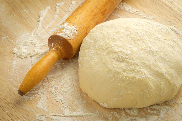 Dough, rolling pin and flour on a wooden background. - Фото, изображение