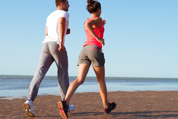 Young couple running together beside the water at the beach. Man - Photo, Image