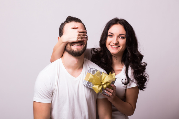 Attractive happy woman with big toothy smile holding boyfriends eyes giving him a present for Valentine's day - Photo, Image