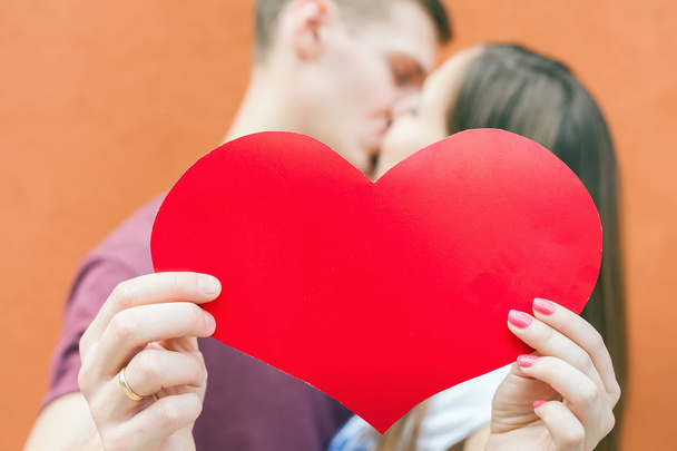 Casal feliz beijando e segurando um grande símbolo do coração
 - Foto, Imagem