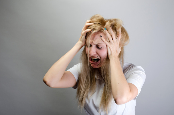 młoda kobieta krzyczy z bólu i trzymając głowę  - Zdjęcie, obraz