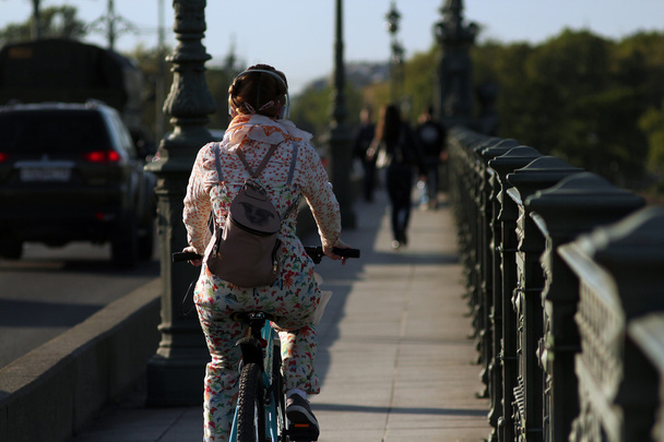 Girl on bike rides along the bridge. - Φωτογραφία, εικόνα