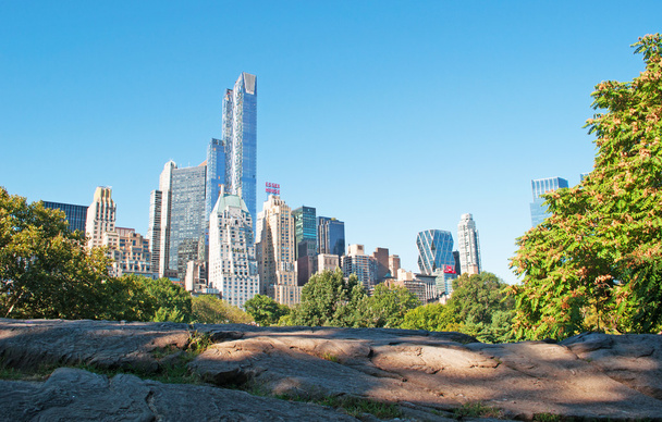画期的なイベントまでさかのぼる何百万年の何百もの目に見える証拠を含む中央公園の有名な露出岩盤からみる都市のスカイラインを望むニューヨーク市: ロック - 写真・画像