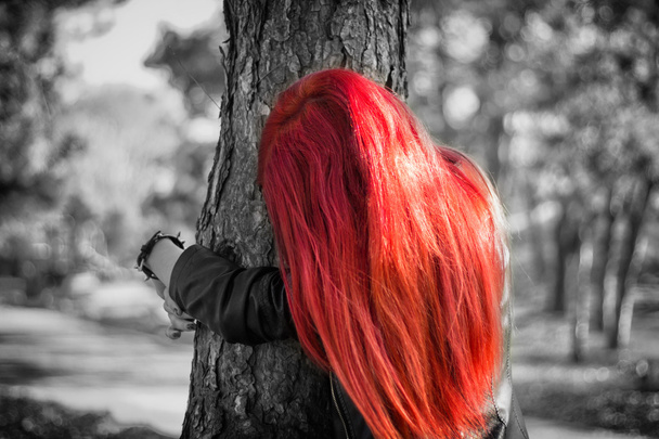 Rudowłosy dziewczyna przytulanie drzewo - czarno-białe zdjęcie z włosów farbowanych - Zdjęcie, obraz