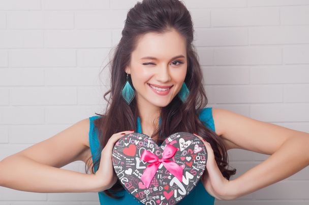 Valentine's Day. Beautiful smiling woman with a gift in the form of heart in his hands - Фото, зображення