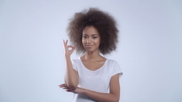 Young woman making OK sign over white background. - Πλάνα, βίντεο