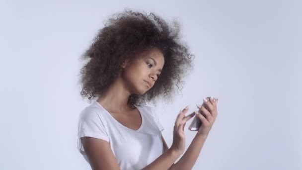Young mulatto girl with mobile phone in studio. - Felvétel, videó