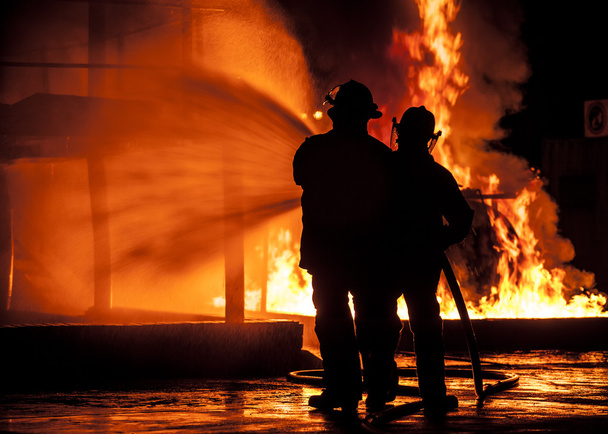 Bomberos usando manguera de agua en llamas
 - Foto, imagen