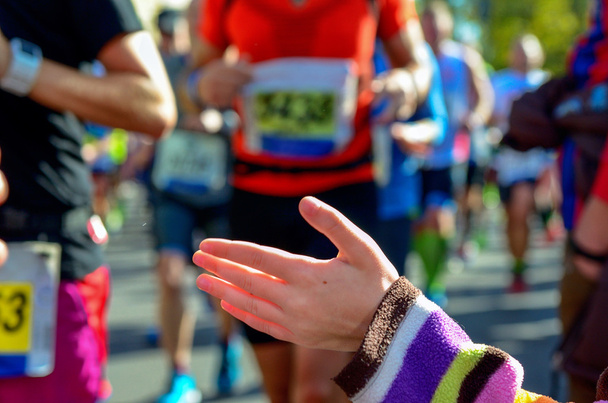 Blurred background: marathon running race, support runners on road, child's hand giving highfive, sport concept - Foto, Bild