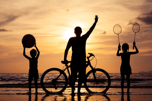 Ο πατέρας και τα παιδιά που παίζουν στην παραλία το ηλιοβασίλεμα στιγμή. - Φωτογραφία, εικόνα