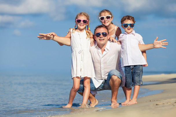 Padre e hijos jugando en la playa durante el día
. - Foto, Imagen
