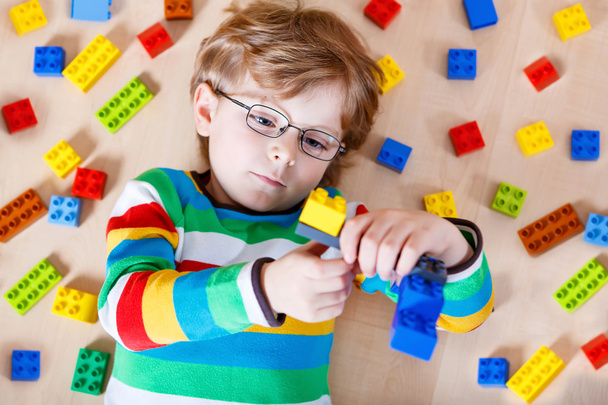 Petit enfant blond jouant avec beaucoup de blocs en plastique colorés
 - Photo, image
