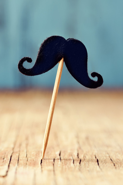 felt mustache in a stick on a wooden surface - Fotoğraf, Görsel