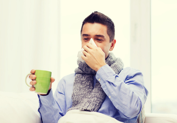 ill man with flu drinking tea and blowing nose - Fotografie, Obrázek