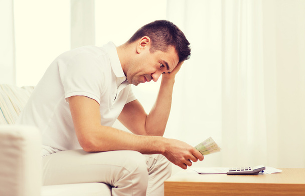 man with money and calculator at home - Foto, Imagen