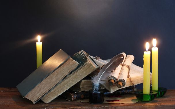 Old books, scrolls, feather pen inkwell and candles on wooden table on blue background - Fotoğraf, Görsel