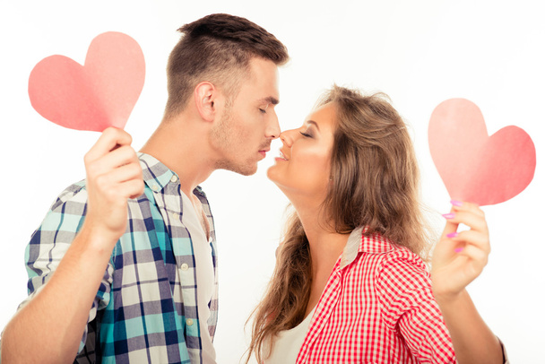 Cheerful couple in love holding two paper hearts kissing each ot - Foto, Imagem