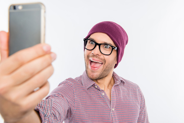 Smiling man in cap and glasses making comic selfie - Foto, afbeelding