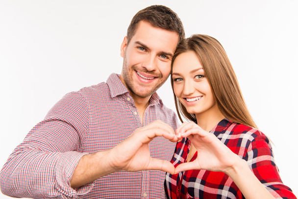 Happy romantic couple in love gesturing a heart with fingers - Fotó, kép