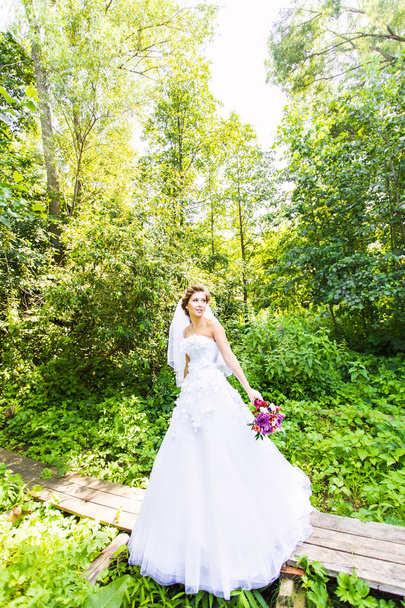 Beautiful bride outdoors with wedding bouquet - Foto, Bild