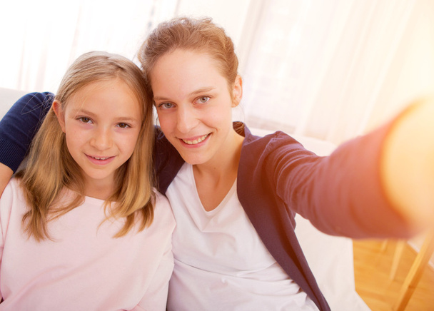 Attractive woman and little sister taking selfie - 写真・画像