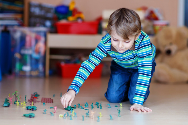 Dziecko, chłopiec bawi się zabawkami żołnierzy pomieszczeniu w przedszkolu - Zdjęcie, obraz