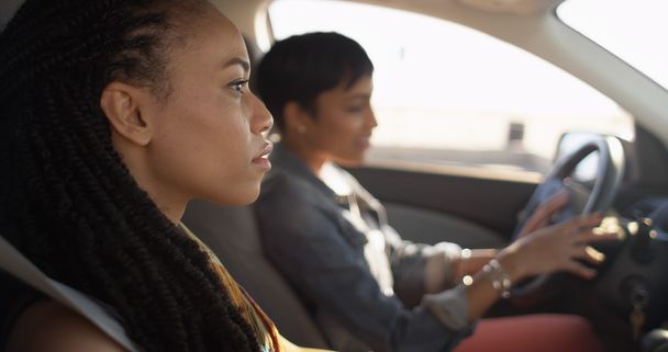 Two black women friends sitting in car talking to each other - Photo, Image
