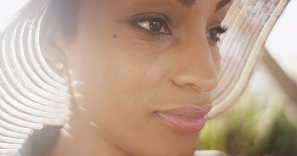 Close up backlit shot of beautiful Black woman wearing sunhat wi - Photo, Image